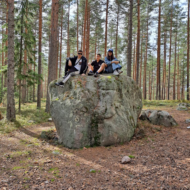 A group resting on a glacial boulder during a forest hike near the camp
